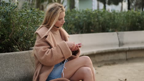 una mujer joven usando el teléfono al aire libre.