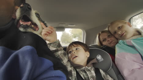 Cheerful-family-with-children-and-dog-travels-by-car