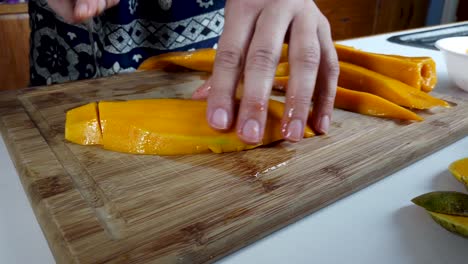 Hände-Würfeln-Frische-Mangofrüchte-Mit-Messer-Auf-Holzschneidebrett,-Nahaufnahme