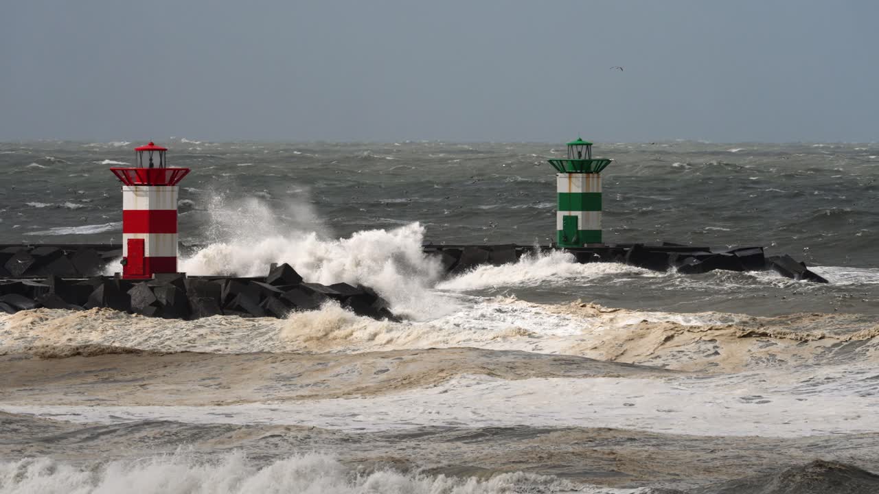 olas tormentosas chocando contra el rompeolas con faros
