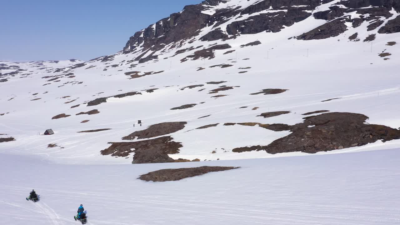 Snowmobiling in a vast, snowy mountain landscape