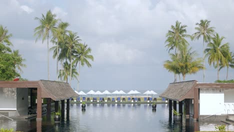 view of the luxury beach lounge beds with umbrella near swimming pool in resort in thailand with sunny summer weather blue sky