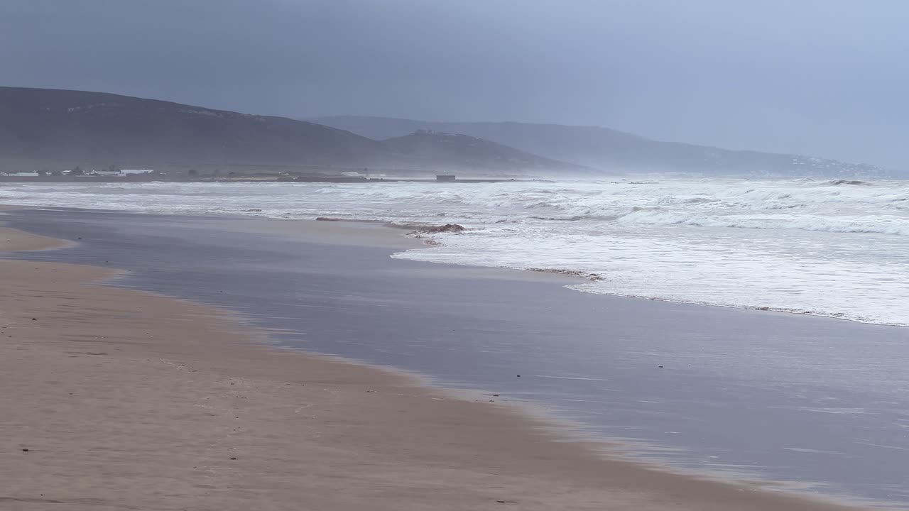 A beach of the Atlantic Ocean in the fog with mountains in the background.