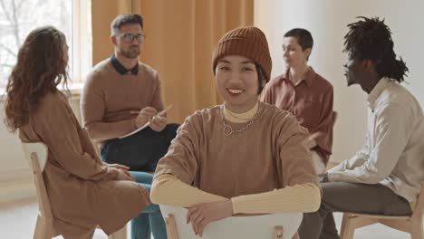 smiling hipster young woman in beanie at group therapy session