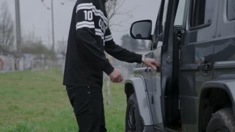 young man opens car door and gets into his car