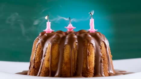 blowing out (twice) pink birthday candles on marble cake with chocolate nougat icing