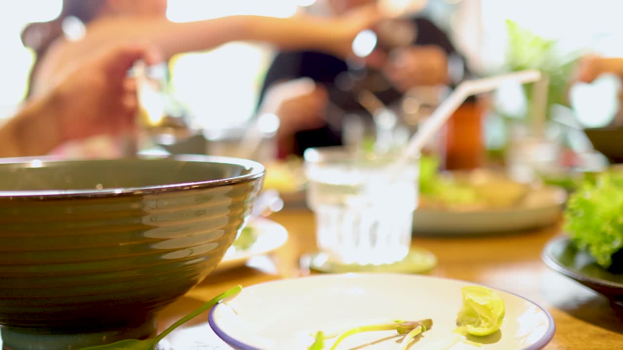 People enjoying Vietnamese pork dishes at a table in Bangkok. Bright lighting, lively atmosphere, and close-up shots of food and interaction