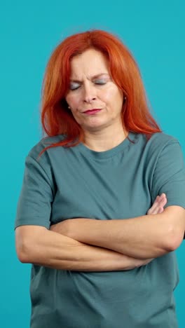 woman with red hair and crossed arms on blue background