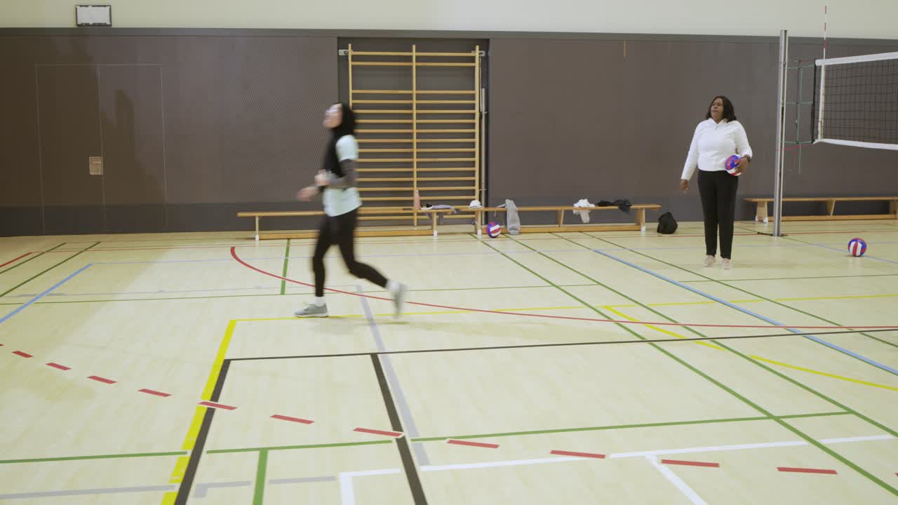 Female players receiving volleyballs from teammate at left line, rotating for passing, copy space