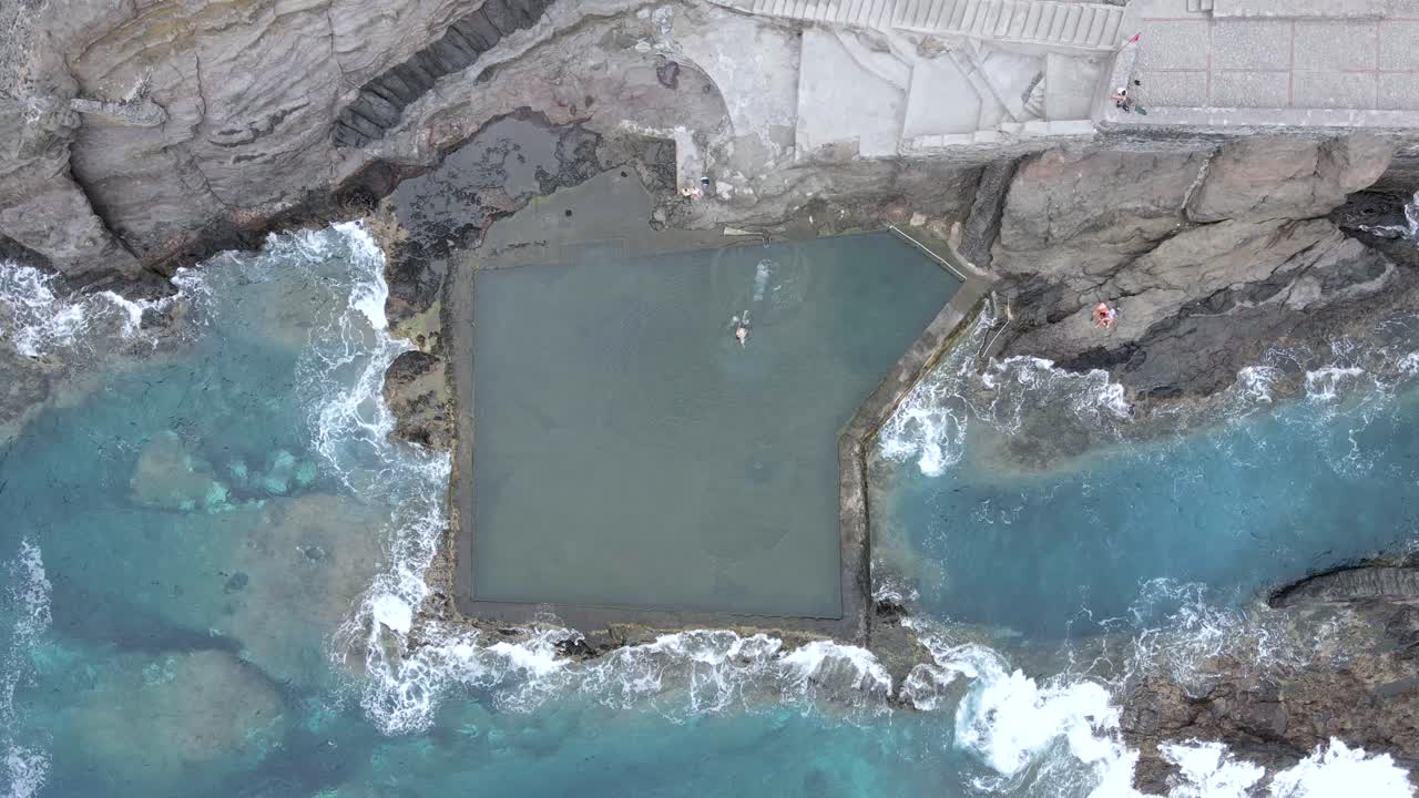 Vista dall'alto di un uomo che nuota nella piscina naturale di acqua marina di Hermigua, La Gomera