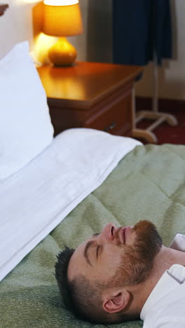 tired businessman on bed. young man falling on bed after a difficult business day. handsome man resting after arrival to a hotel room. vertical video