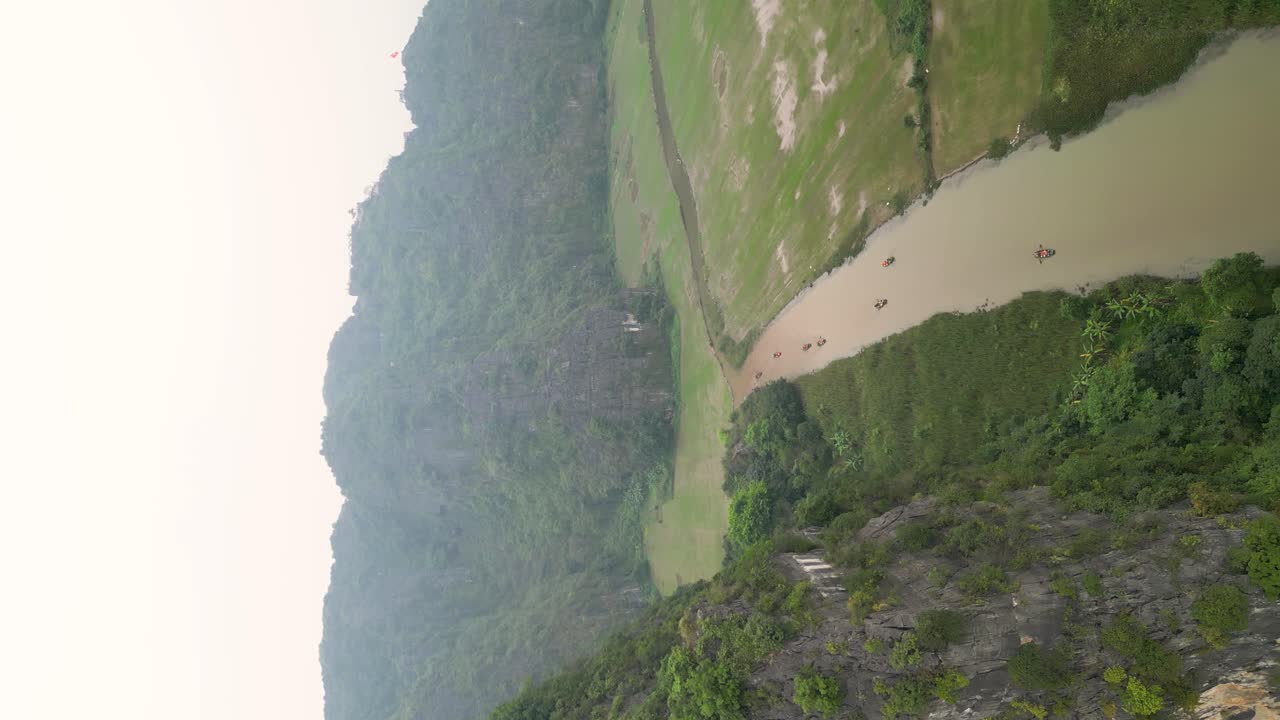 vertical shot wooden boats sling in the Ngo Dong river at the Hang Mua caves