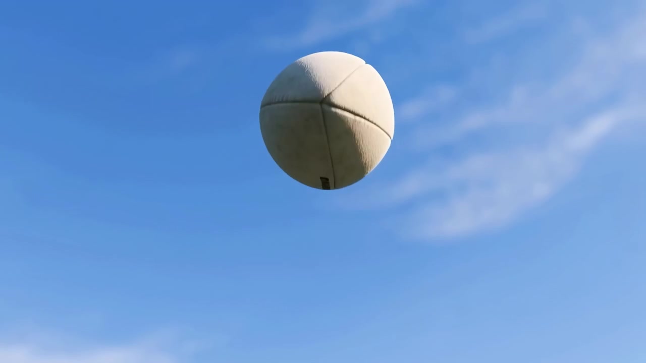 Off-white rugby ball rotates gently in open air against saturated blue sky and thin clouds, with low-angle view, bright daylight, worn surface, and strong copy space for sports use