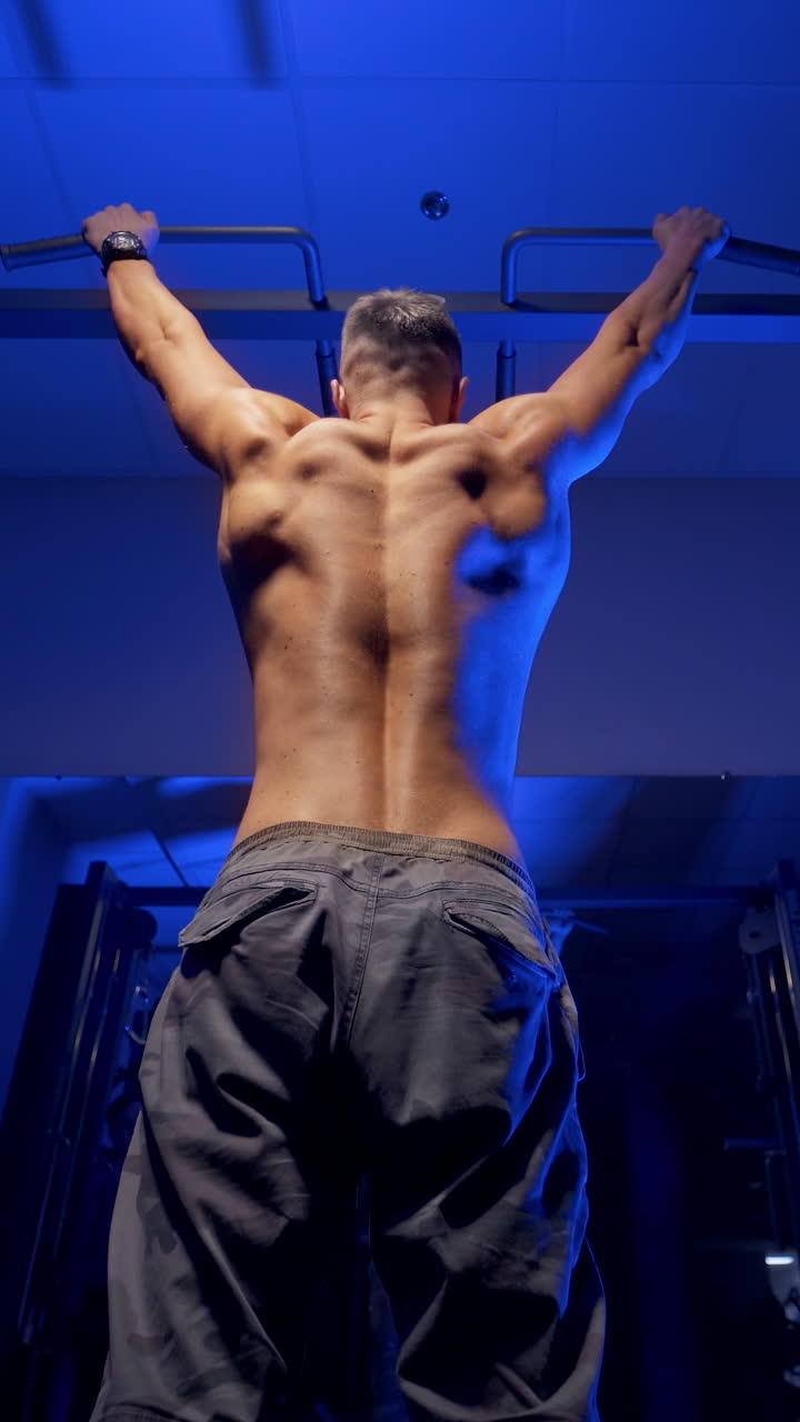 Man doing pull up exercise. Young man doing pull ups on horizontal bar indoors. Vertical video