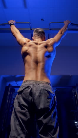 man doing pull up exercise. young man doing pull ups on horizontal bar indoors. vertical video