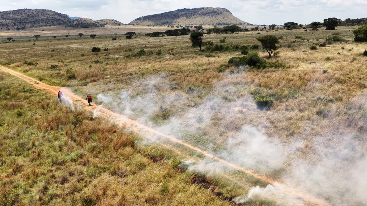 I vigili del fuoco eseguono un controfuoco per gestire un incendio boschivo in avanzamento, in una prateria aperta