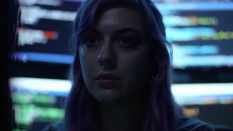 a focused individual analyzing code in a dimly lit environment, surrounded by multiple computer screens displaying colorful programming syntax
