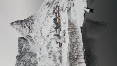 Tiro-Vertical-Del-Paisaje-Nevado-De-Montañas,-Embarcadero-Y-Puerto-Deportivo-En-Reine,-Lofoten-Durante-El-Invierno