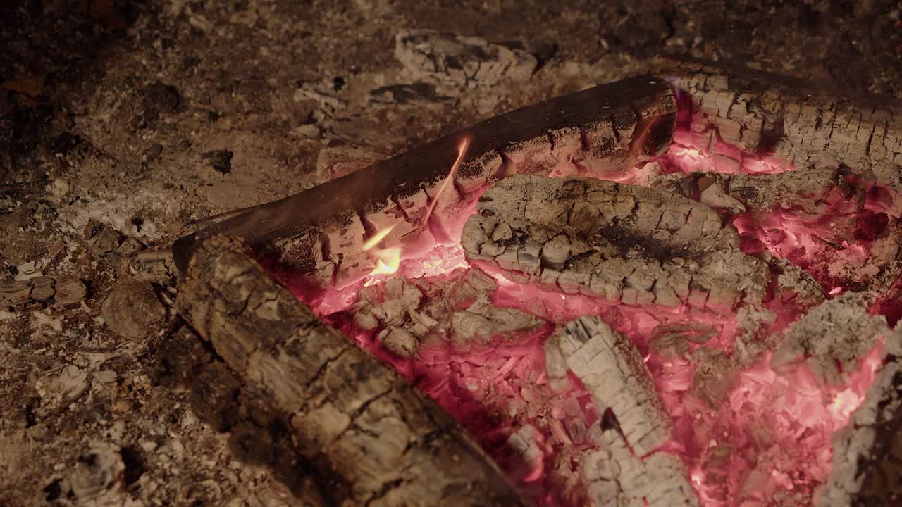 chamas quentes vermelhas brilhantes permanecem enquanto o fogo do acampamento queima os troncos em cinzas.