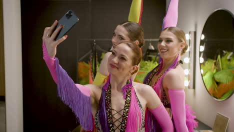 three showgirls taking a selfie in the backstage