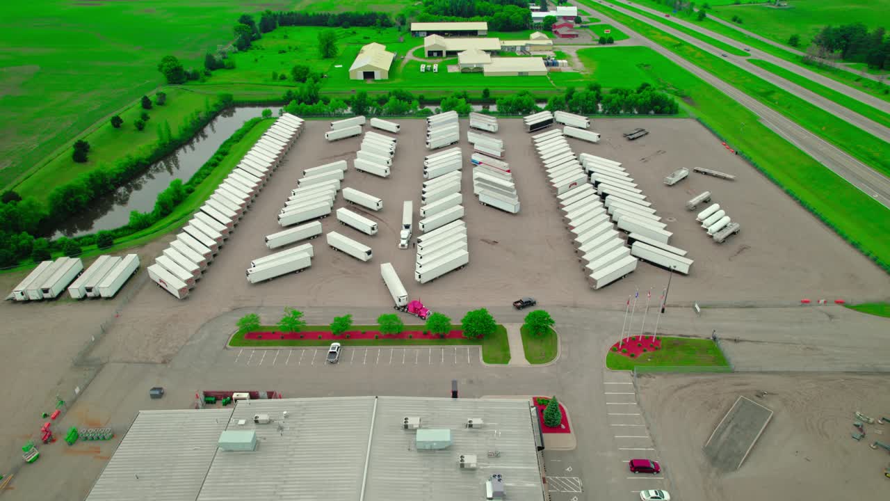 Aerial view of Ritchie Bros. Auctioneers facility, showcasing parked dry van trailers and trucks near a highway.