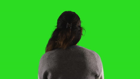 Close-Up-Studio-Rear-View-Shot-Of-Female-Teacher-Or-Businesswoman-Facing-Away-From-Camera-Towards-Green-Screen