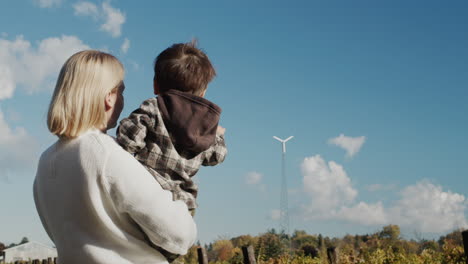 a mother shows her son a wind generator installed on their farm.