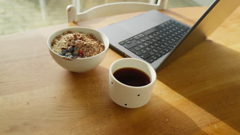 configuración de trabajo remoto con computadora portátil, cuenco de granola saludable y café