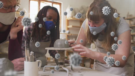 Composite-video-of-covid-19-cells-against-group-of-diverse-female-potters-working-on-pottery-wheel