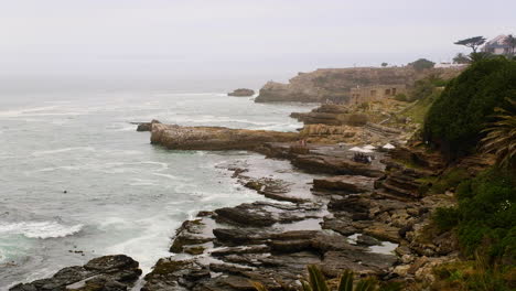 rugged hermanus coastline on misty morning - people whale watching from rocks