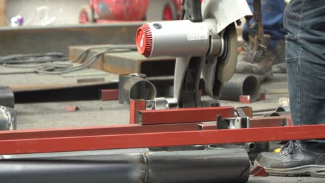 male worker cutting a metal tubular with cut-off machine - close up