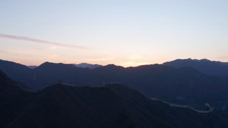 aerial shot of the great wall of china in mountains at sunset