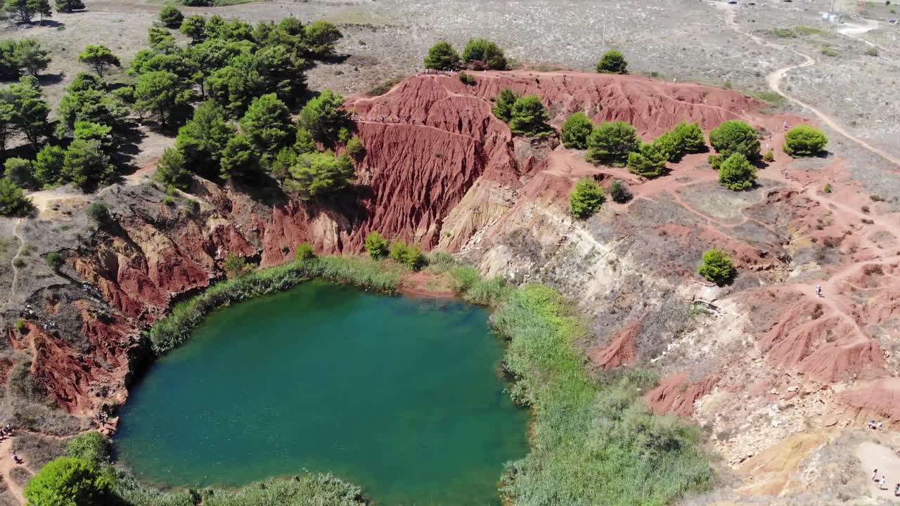 Drone rotates over cava di bauxite in Puglia revealing the lake and the color contrasts
