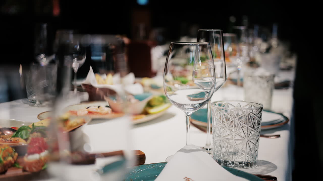 Refined restaurant table setting with crystal glasses, plates, and gourmet dishes in the background