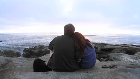 a couple snuggle together on a beach