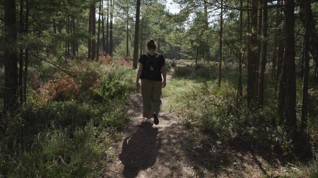 white woman in her thirties walks along a forest path in Stilo, Poland