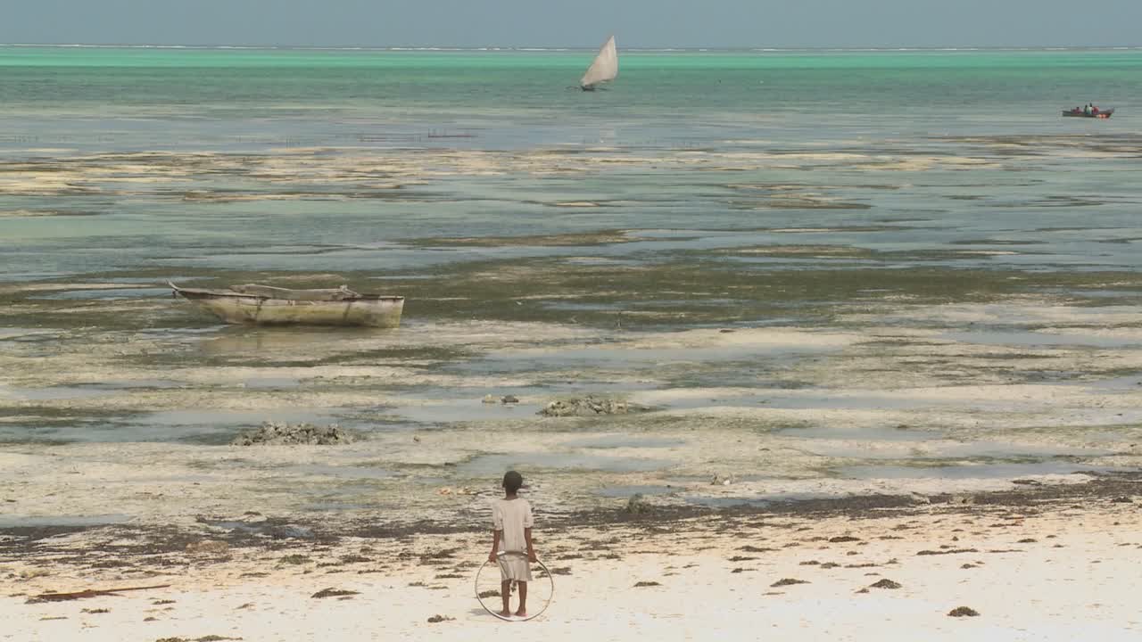 한 소녀가 먼 범선을 바라보며 해변에 장난감 반지를 들고 서 있다