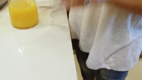 mujer con pierna protésica vertiendo jugo de naranja en un vaso de 4k