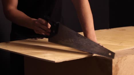 a carpenter running a saw over a thin piece of wood to start a groove to cut