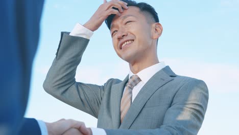 양복을 입은 두 명의 사업가들이 손을 흔들고 있습니다.