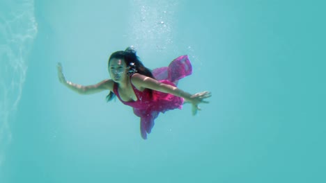 Brunette-in-evening-gown-diving-into-swimming-pool