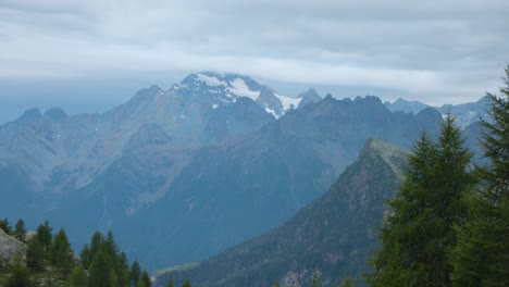 Panoramic-tilt-up-view-of-lush-forest-covered-mountains-and-cloudscape-in-Alpe-Prabello,-Italy