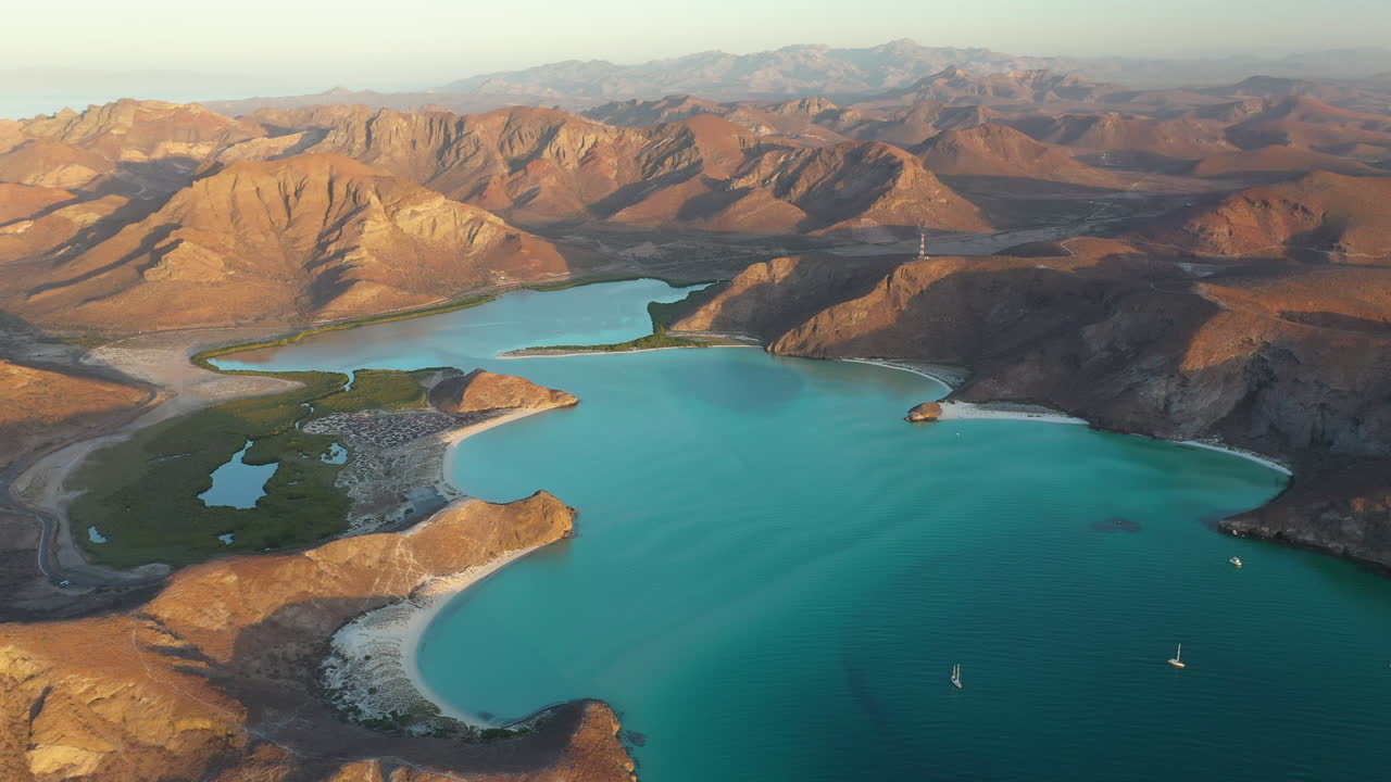 toma cinematográfica de drones de la playa balandra, pasando por las colinas rojas, aguas turquesas y playas de arena blanca, toma amplia con barcos anclados en la bahía