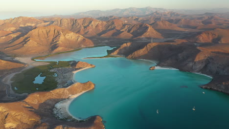 cinematic drone shot of balandra beach, passing over the red hills, turquoise waters and white sand beaches, wide shot with boats anchored in bay