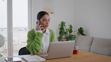mujer de hombros hablando llamada telefónica apartamento de primer plano. mujer confundida bebiendo té