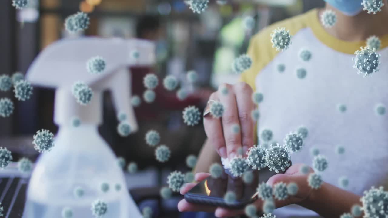 코로나19 세포를 검사한 여성 마스크를 쓰고 사무실에서 소독제로 스마트폰을 청소하고 있습니다.