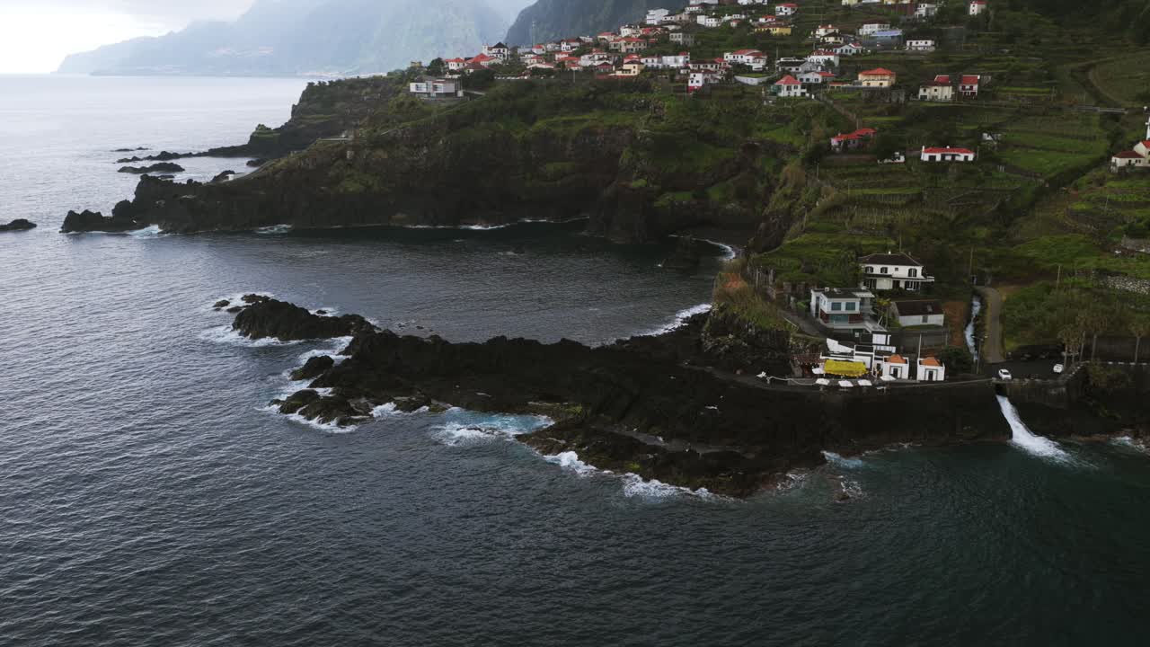 Vila de Seixal na costa irregular, cachoeira fluindo para o oceano e bela paisagem na Madeira, Portugal. Drone aéreo