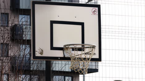 Static-shot-of-a-weathered-hoop-and-backboard-on-an-outside-court