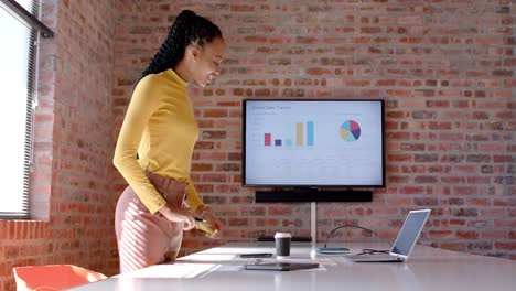 African-american-casual-businesswoman-looking-at-documents-using-laptop-in-office,-slow-motion