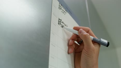 person writing on a wall calendar